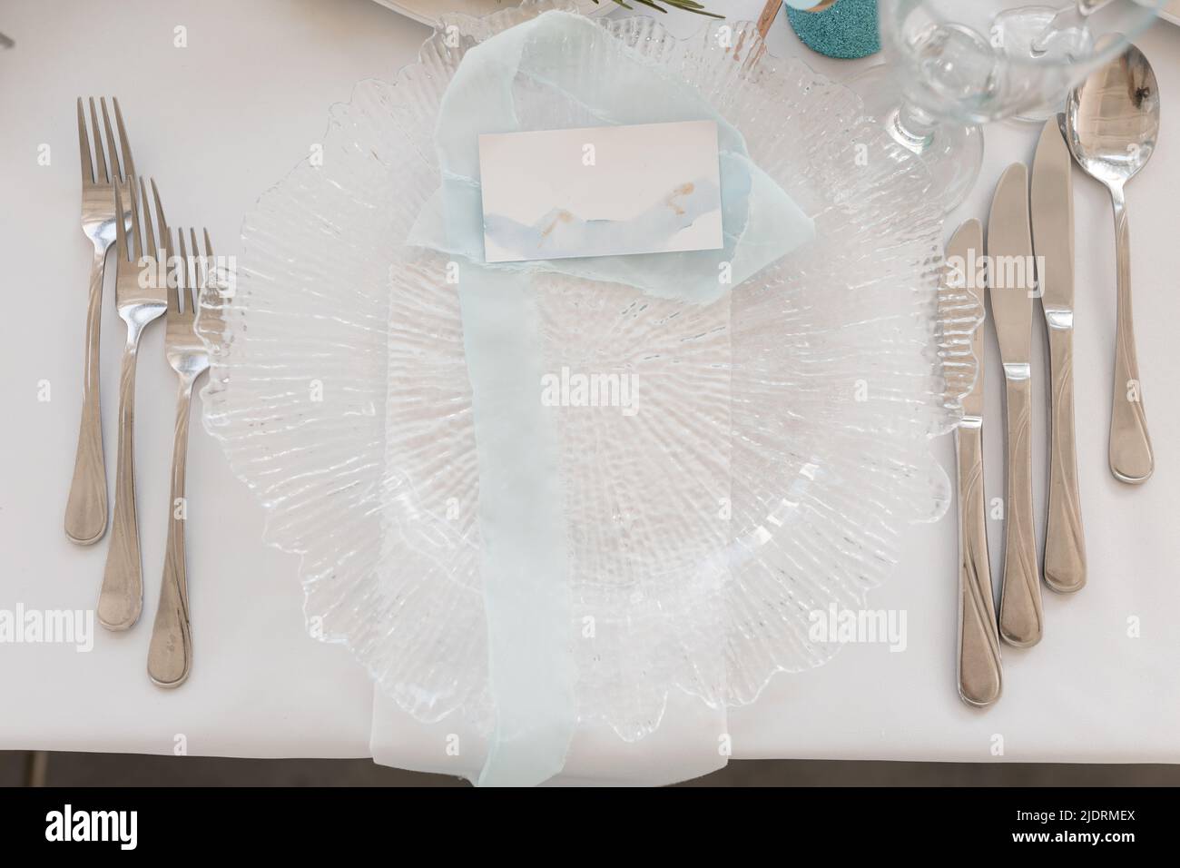 Festive table setting with card for name on white tablecloth closeup top view. Place identity, decorated hall, event celebration. Holiday, elegant and Stock Photo