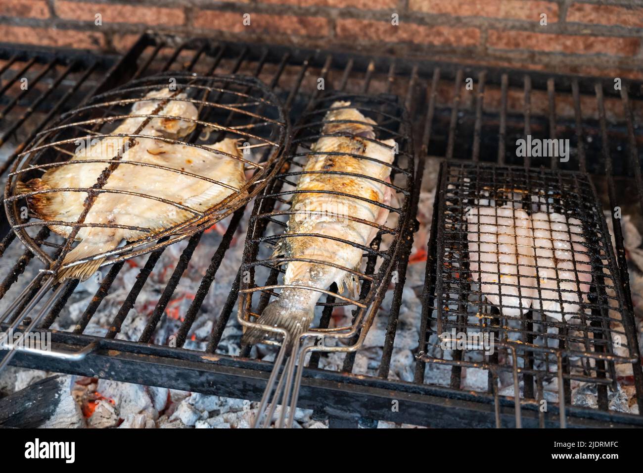 Fresh fish grilling on old charcoal parrillas white fish sea bass and