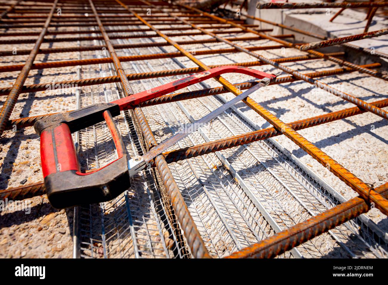 A hand hacksaw for metal set on rusty square reinforcing mesh that was