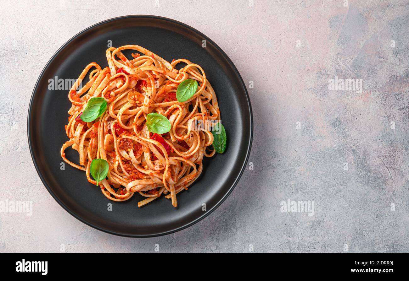 Italian linguini pasta with tomato sauce and fresh basil on a light