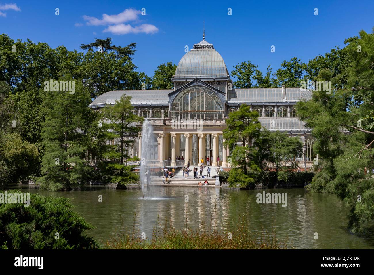 Crystal Palace. Building located in the Retiro Park in Madrid with its glass windows surrounded by trees and green vegetation on a sunny day Stock Photo