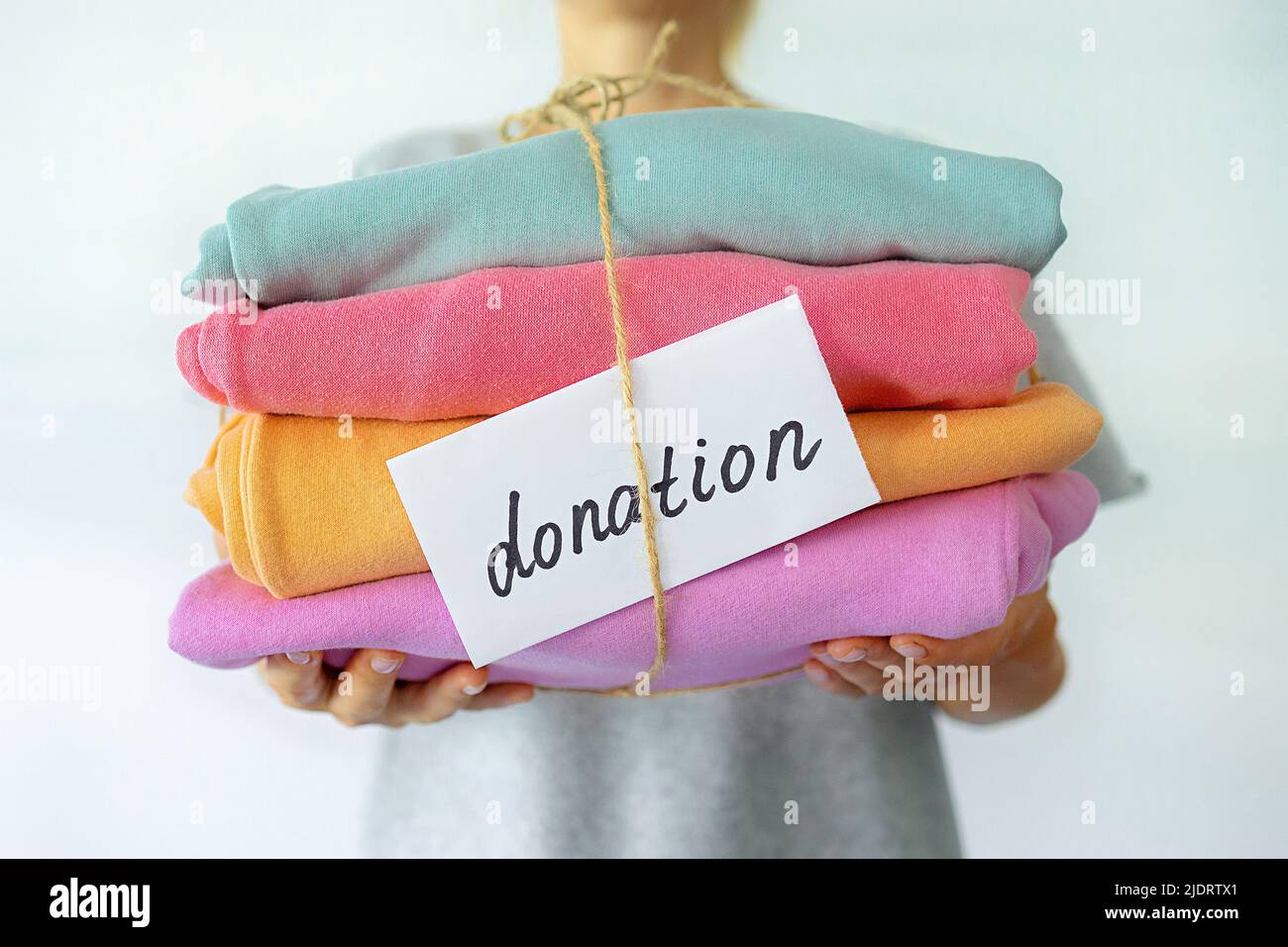 Woman's hand holding a stack of clothes. Clothes Donation, Renewable