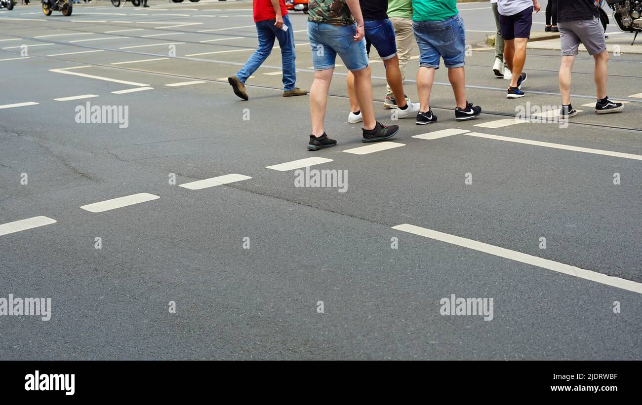 Men crossing a street wearing shorts and sneakers. Stock Photo