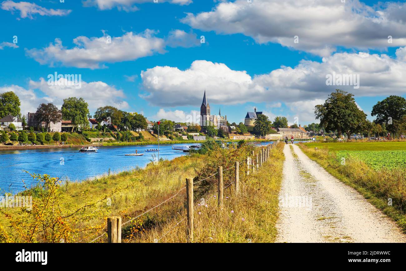 Beautiful dutch rural landscape, cycle path to ferry station, medieval town church tower, river Maas - View from Beesel on Kessel, Netherlands Stock Photo