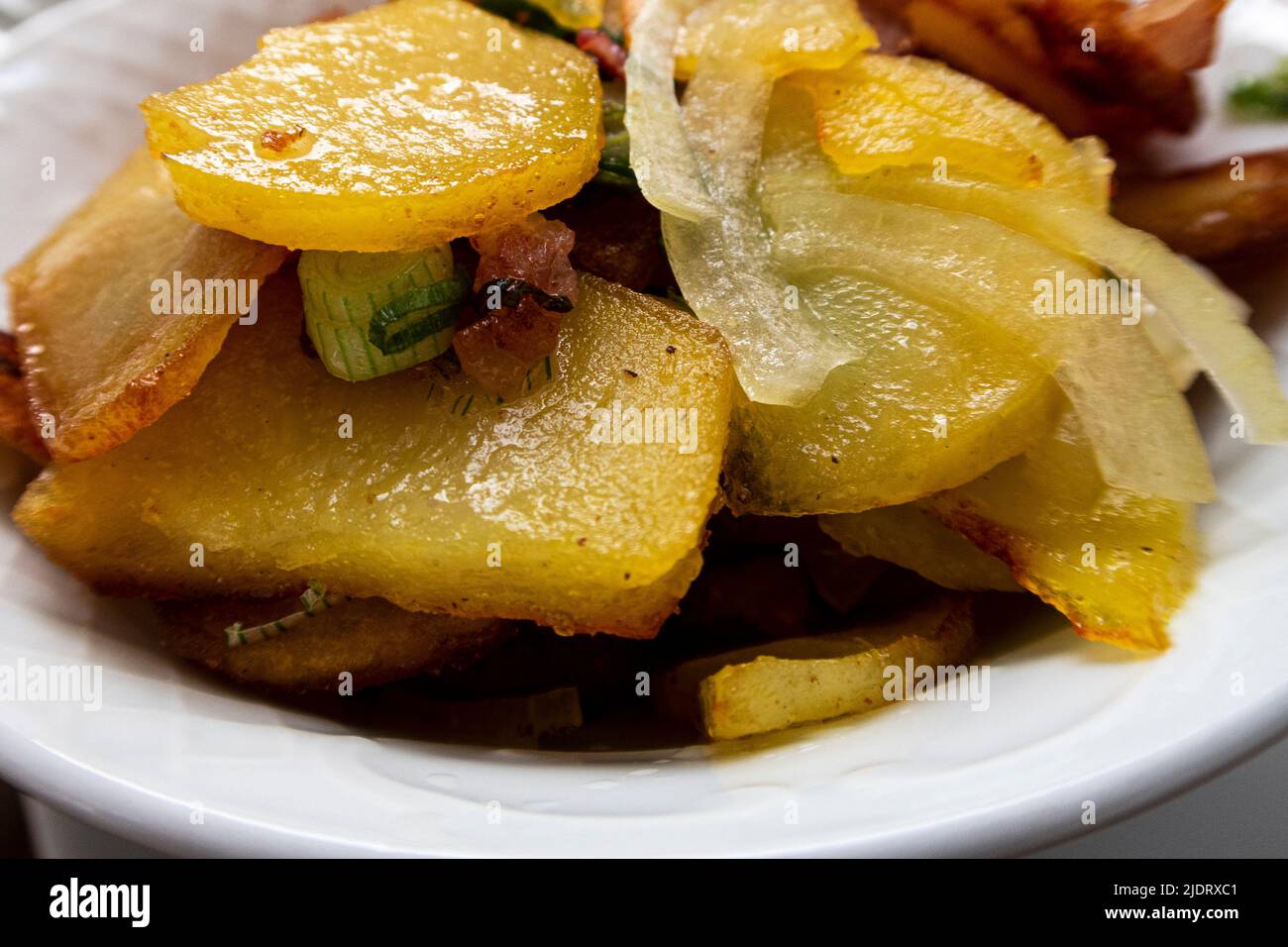 Close-up of delicious, golden yellow fried fried potatoes with bacon and onions Stock Photo