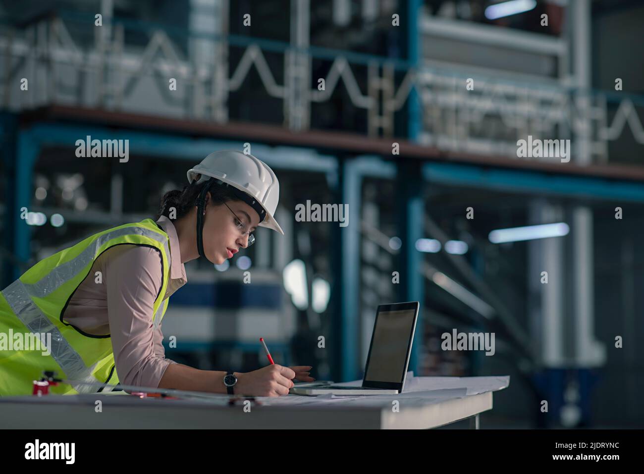 Female architect making a blueprint in the construction site of a factory Stock Photo