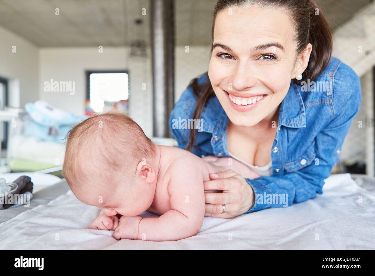Happy smiling mother and her newborn baby on the changing table in the living room Stock Photo