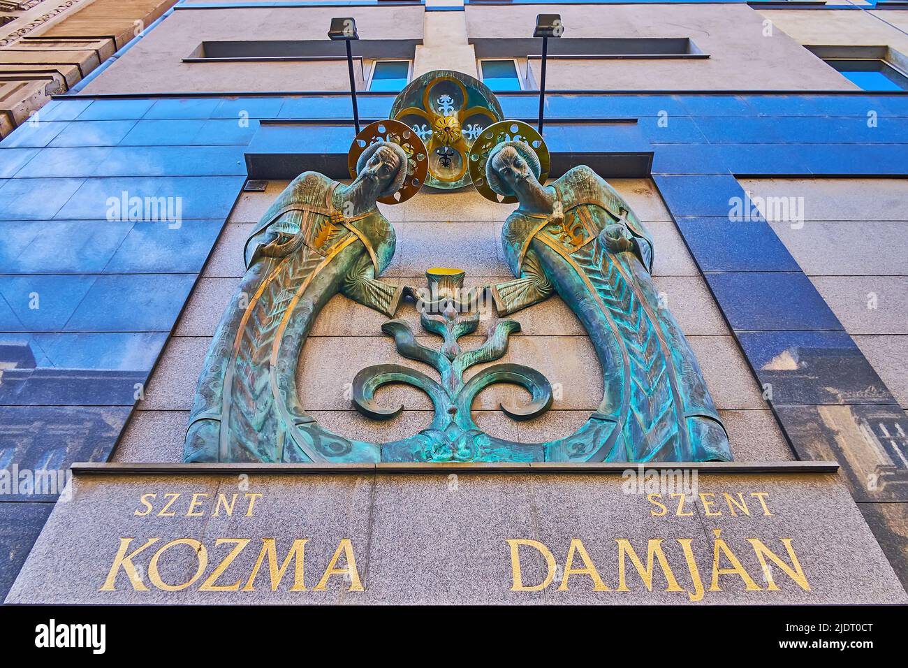 BUDAPEST, HUNGARY - FEB 27, 2022: The modern bronze wall sculpture of St Cosmas and Damian (Szent Kozma, Szent Damjan), on house wall on Hercegprimas Stock Photo