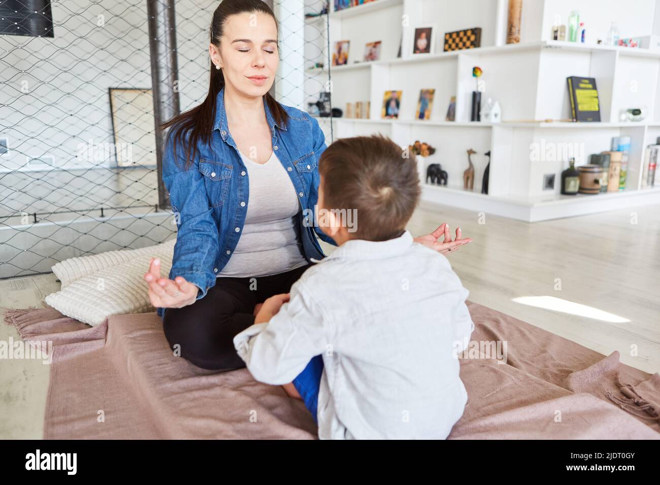 Mother and son meditating with eyes closed for relaxation in the living room Stock Photo