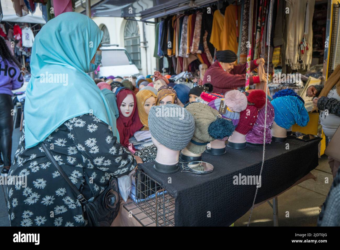 A Muslim woman helps a customer find an appropriate head scarf or hijab from a series of mannequins in a local market in Turin, Italy Stock Photo