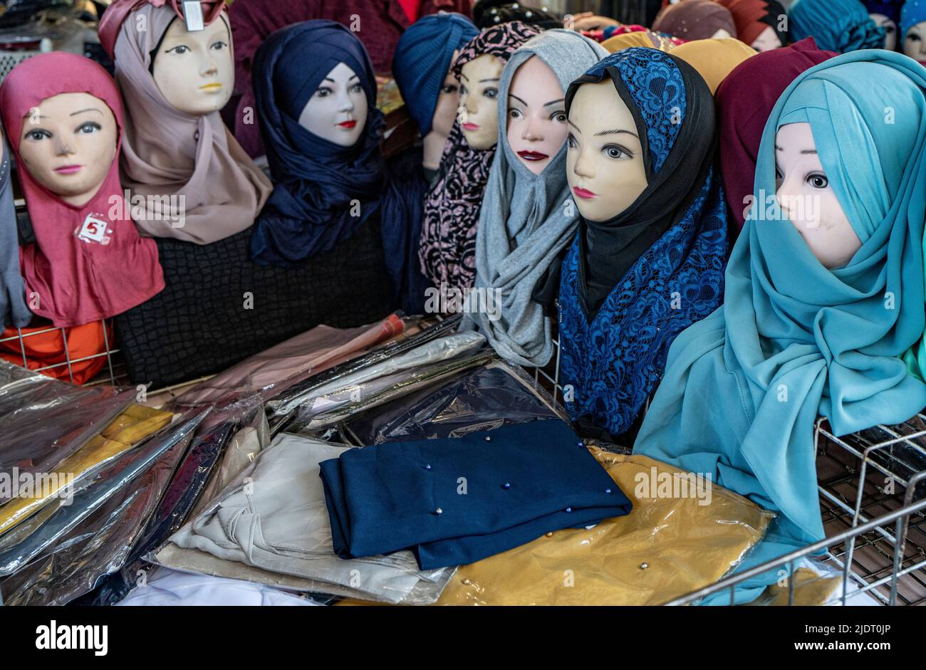 A series of mannequins wearing colorful head scarves or hijabs in a market stall in Turin, Italy Stock Photo