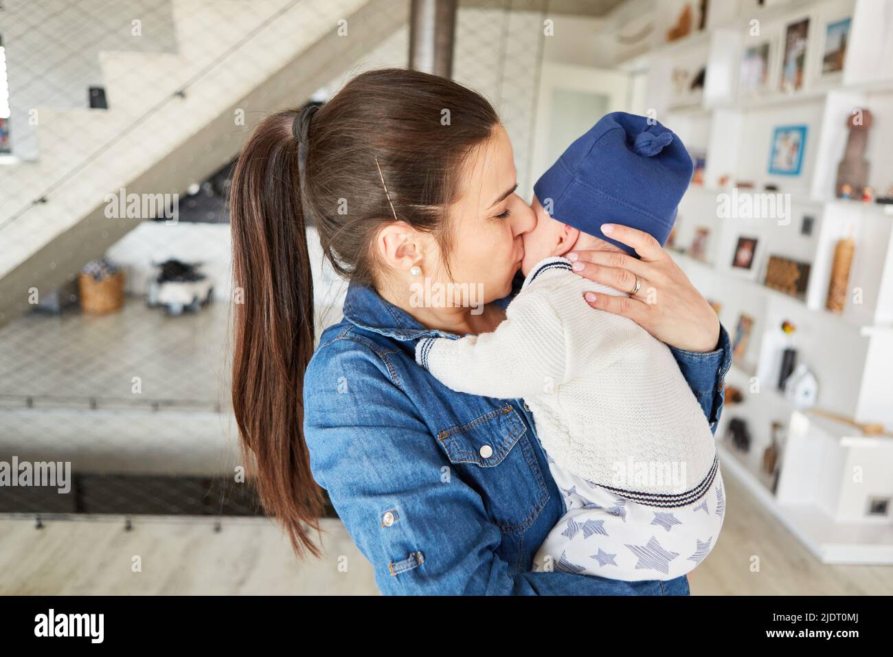Happy mother with baby in her arms gives her infant a loving kiss Stock Photo