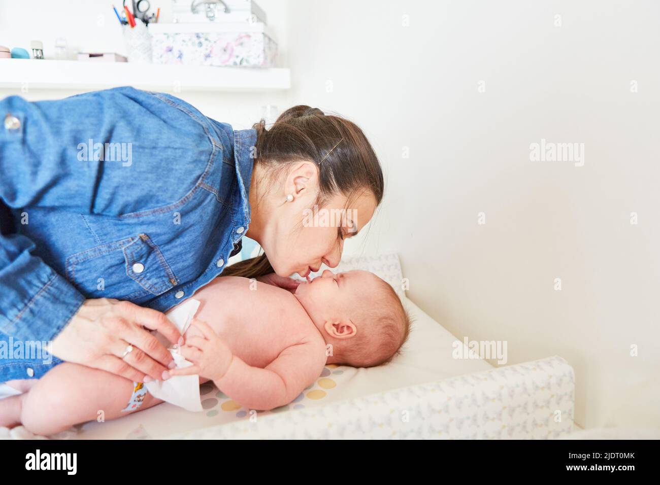 Mother gives her baby a loving kiss on the changing table while changing the diaper Stock Photo