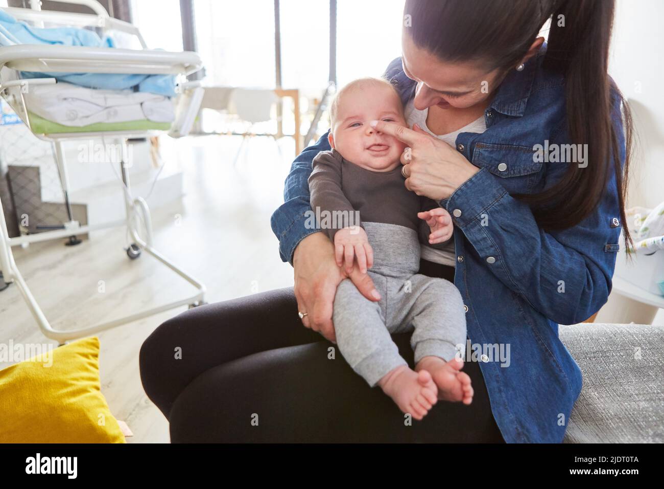 Happy mother lovingly stroking her baby's nose for motherly love and intimacy Stock Photo
