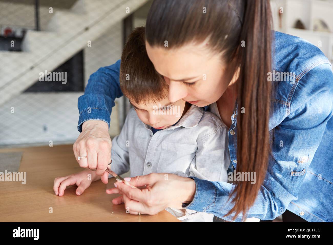 Caring and careful mother cutting nails of her son as body care Stock Photo
