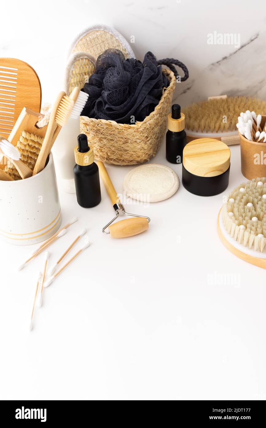 Wooden toothbrushes with natural bristles in a ceramic glass, face and skin care products, black bottles with a pipette and a jar of cream Stock Photo