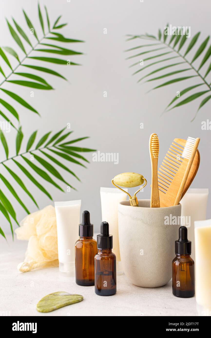 Wooden toothbrushes with natural bristles in a ceramic glass, face and skin care products, bottles with a pipette and a jar of cream, bath accessories Stock Photo