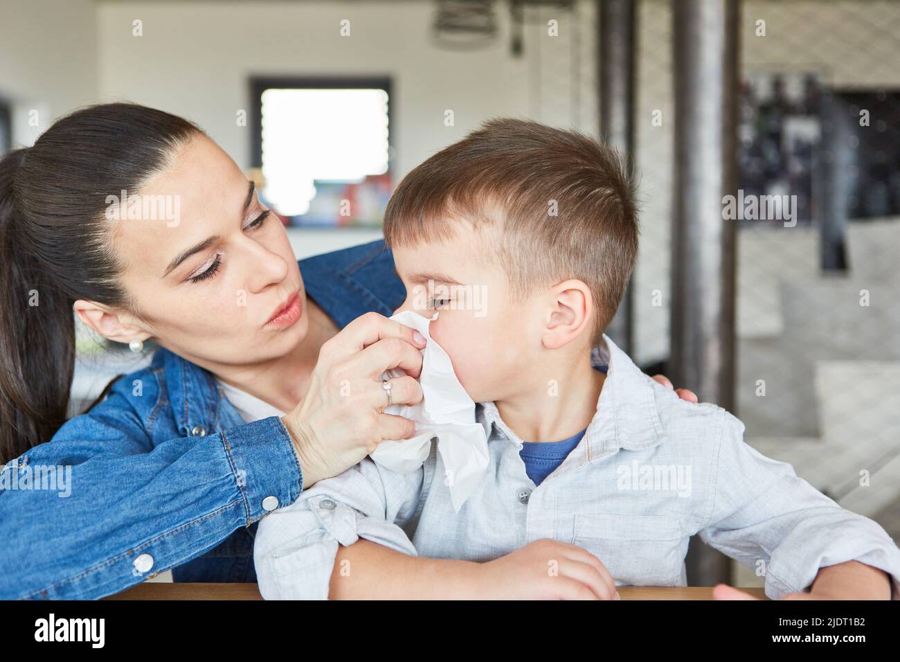 Caring mother blowing her son nose with cold or runny nose at home Stock Photo