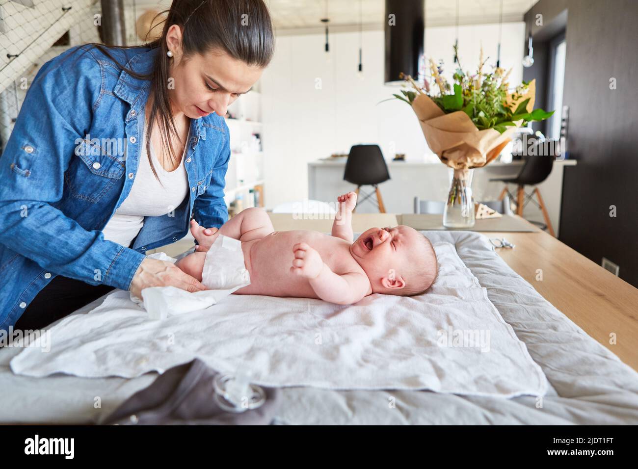 Mother changing baby's diaper on the changing table at home in the living room Stock Photo Alamy