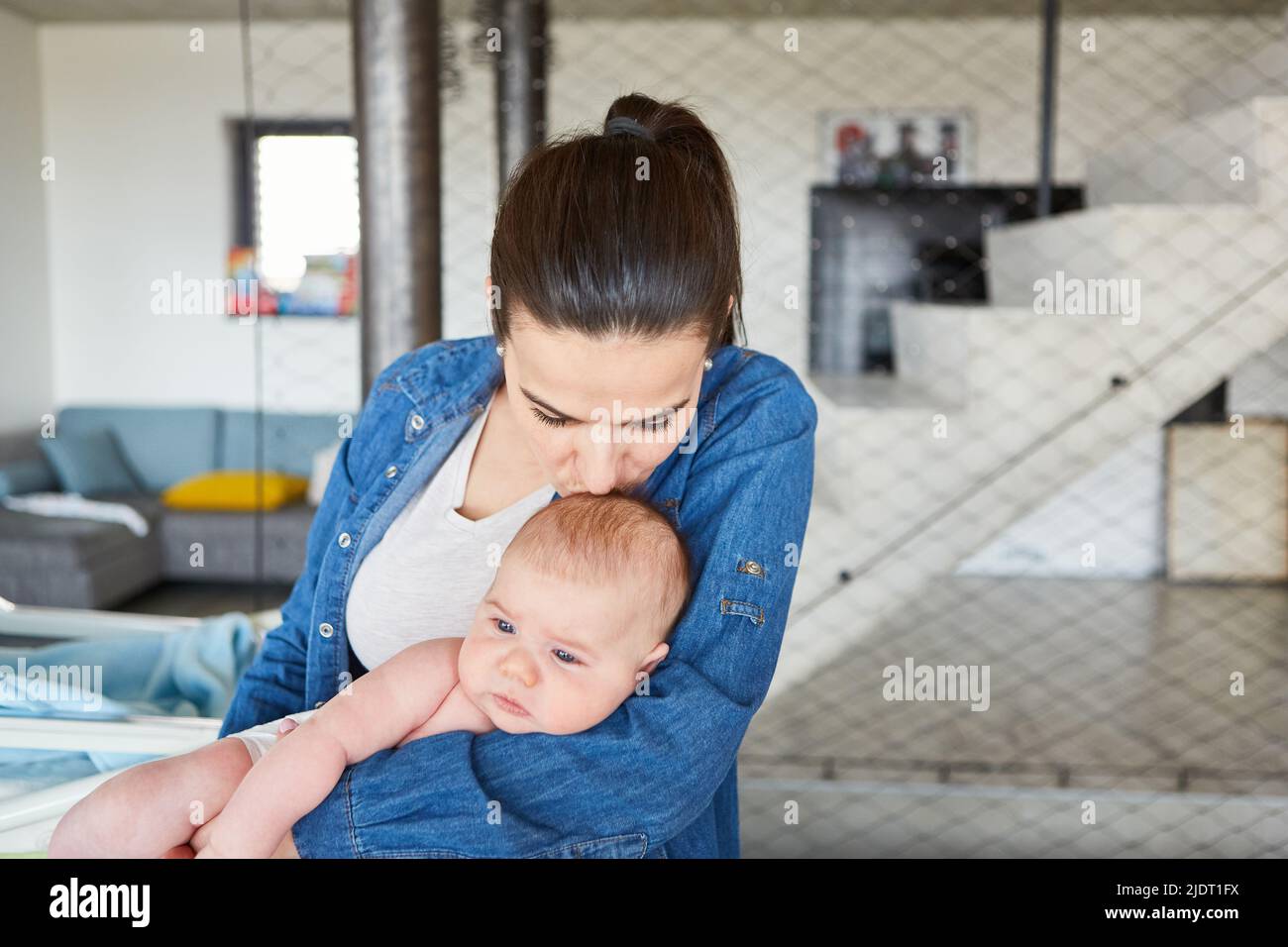 Mother gives her baby a kiss on the forehead as a concept of love and security Stock Photo