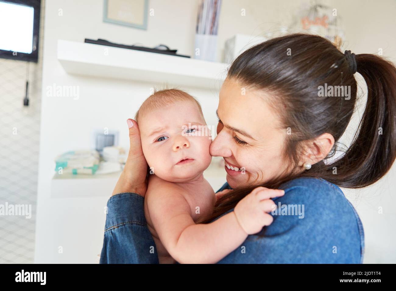 Happy woman as a mother holds her newborn baby safely and lovingly in her arms Stock Photo