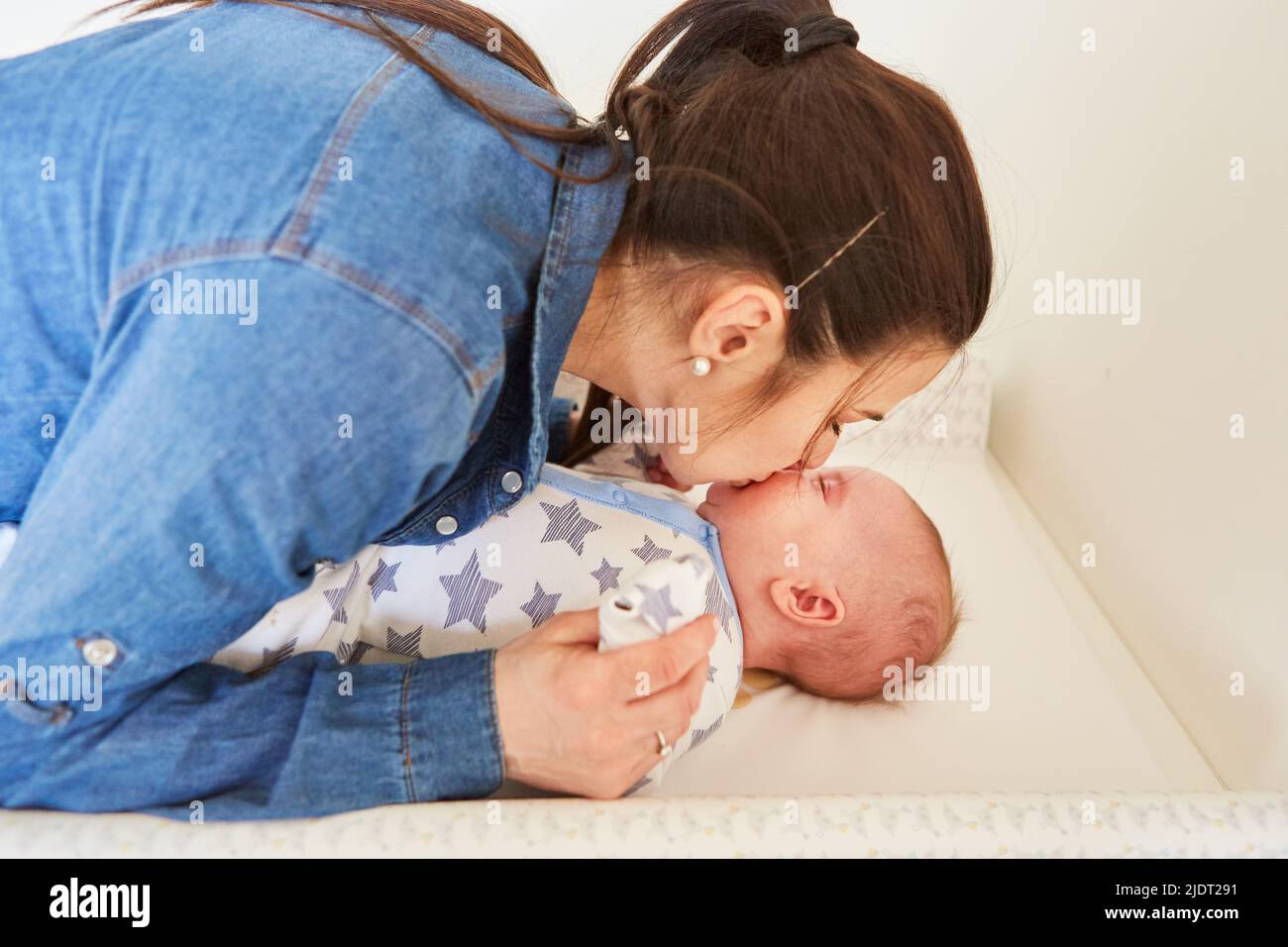 Mother lovingly kisses her baby on the changing table after changing the diaper Stock Photo