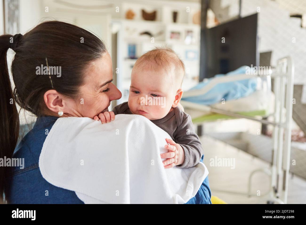 Happy mother lovingly holding her newborn baby in her arms at home in the living room Stock Photo