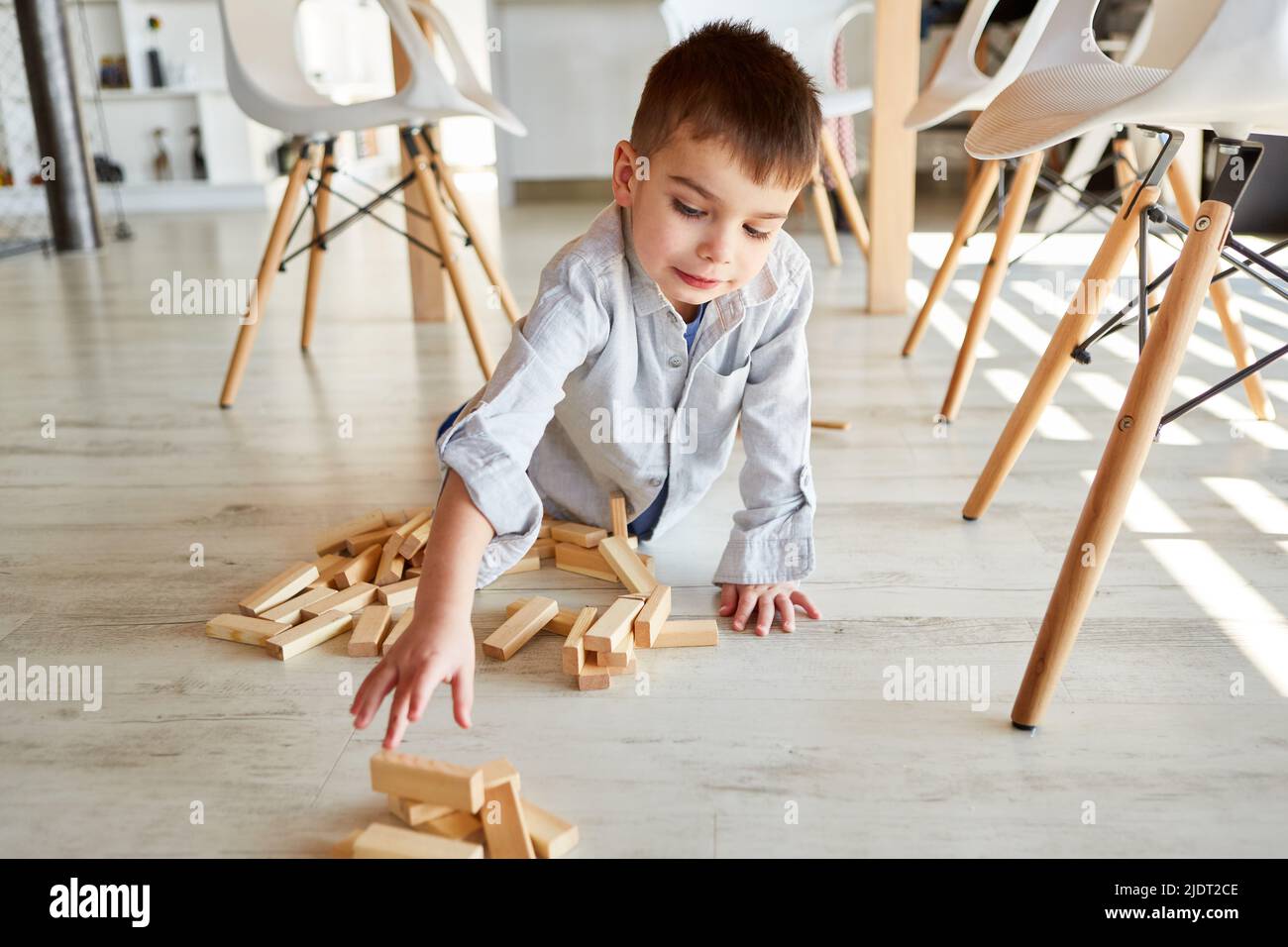 Little boy playing with wooden blocks on the floor in the living room at home Stock Photo
