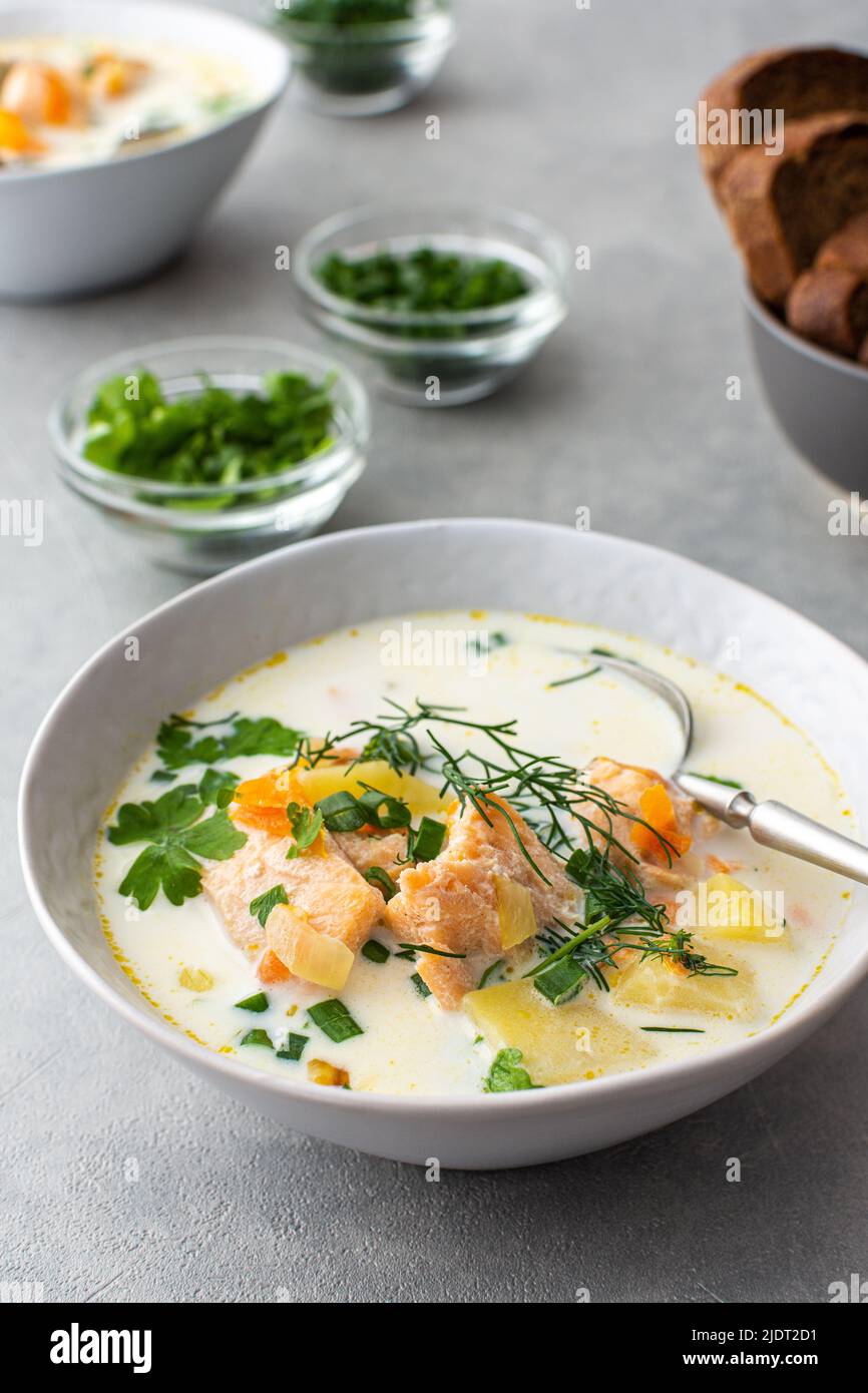 Norwegian salmon red fish soup with vegetables, herbs and cream, top view on the dining table Stock Photo