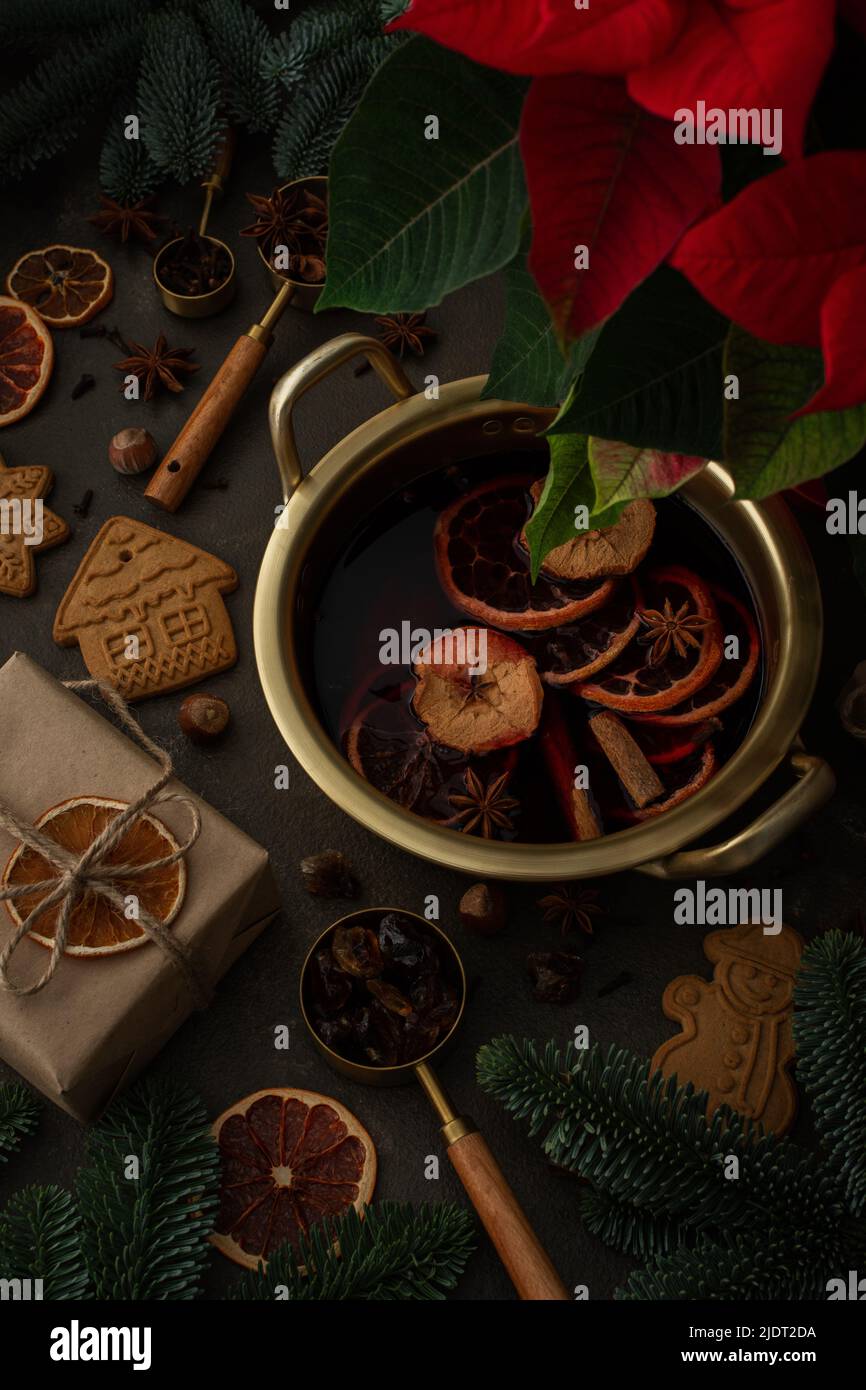Christmas hot alcoholic drink mulled wine in a pan with citruses, aromatic spices, cinnamon and dried fruits among the spruce branches Stock Photo
