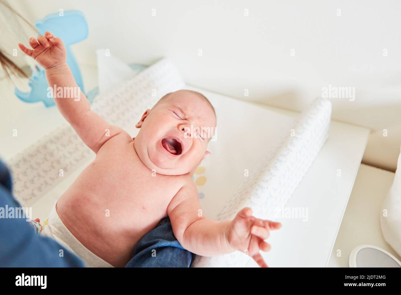 Mother changing the diaper of a crying baby on the changing mat Stock Photo