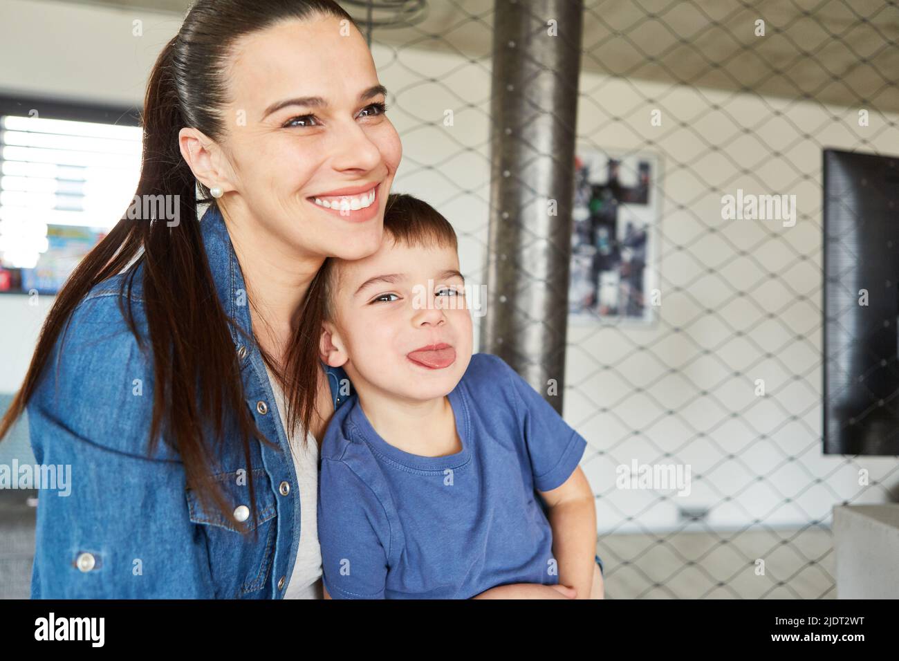 Little boy sits next to his mother and sticks his tongue out as a naughty boy Stock Photo