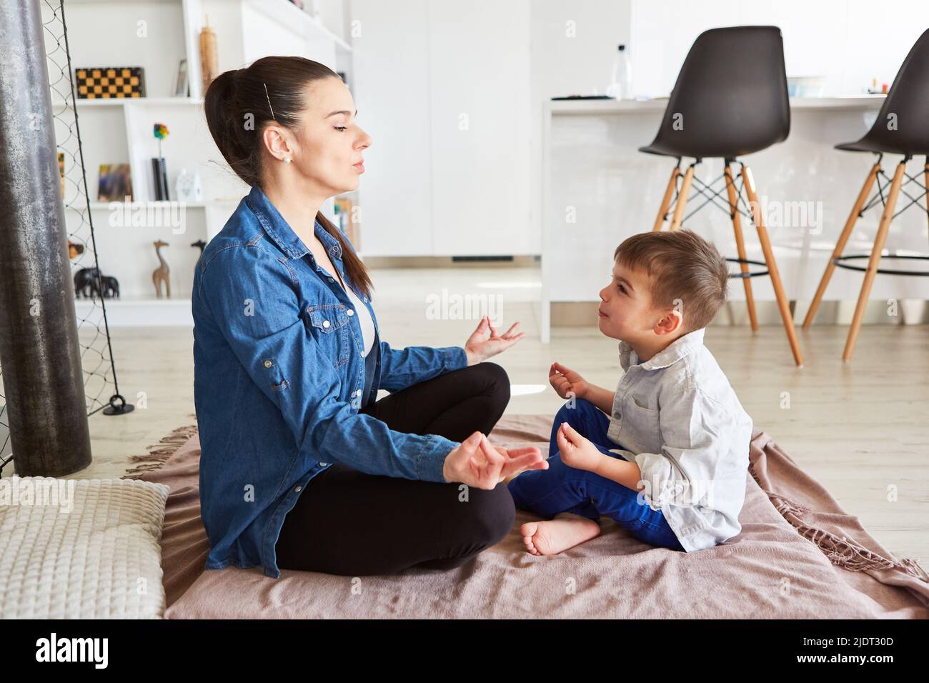 Mother and son relaxing doing yoga and meditating together at home in the living room Stock Photo