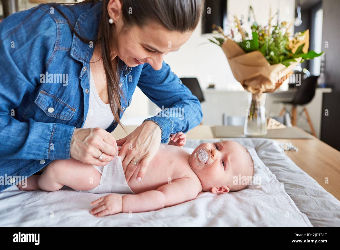 Mother swaddles baby with diaper at home for care in the living room Stock Photo