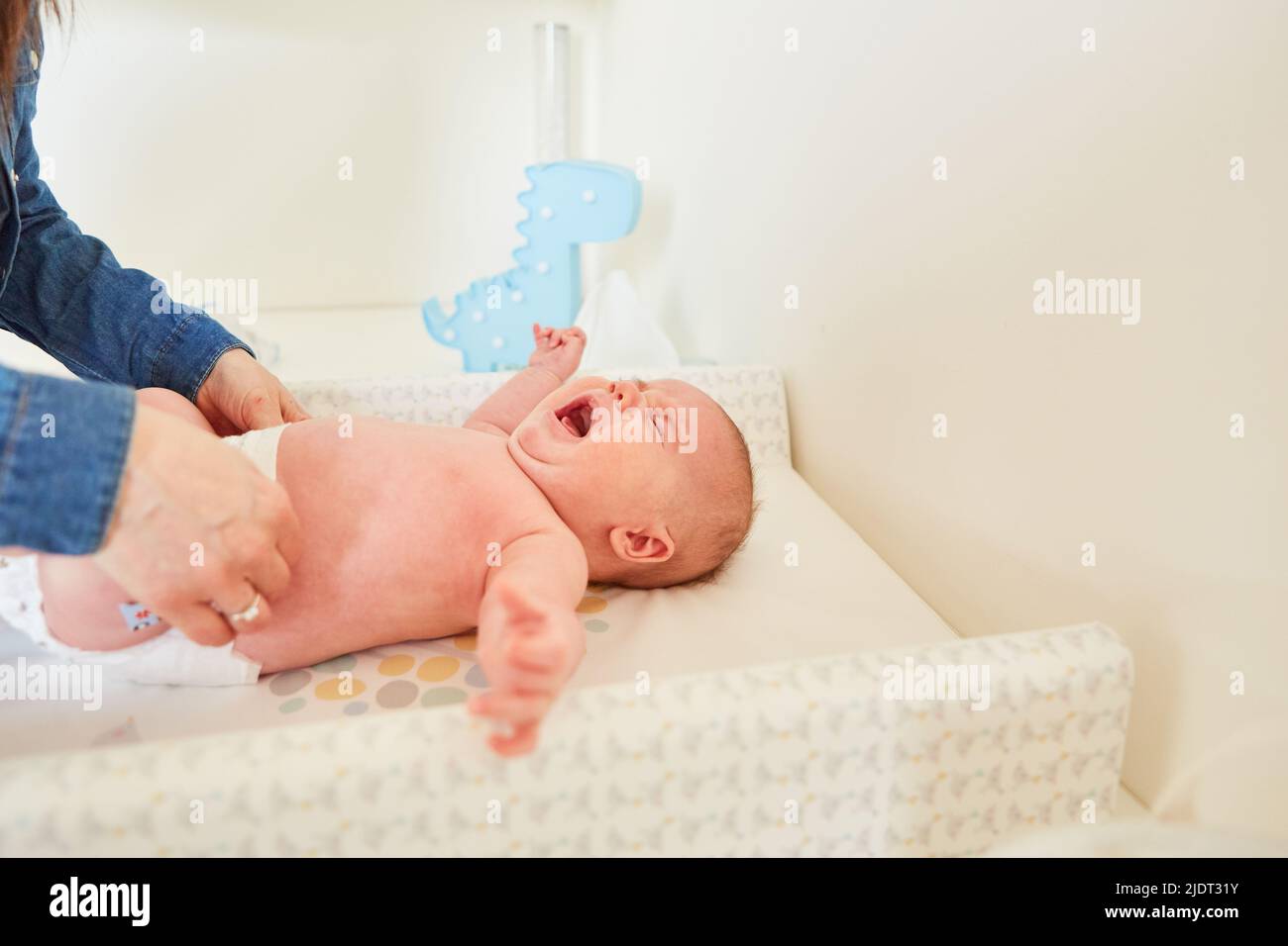 Crying baby when changing diapers by the mother on the changing table Stock Photo