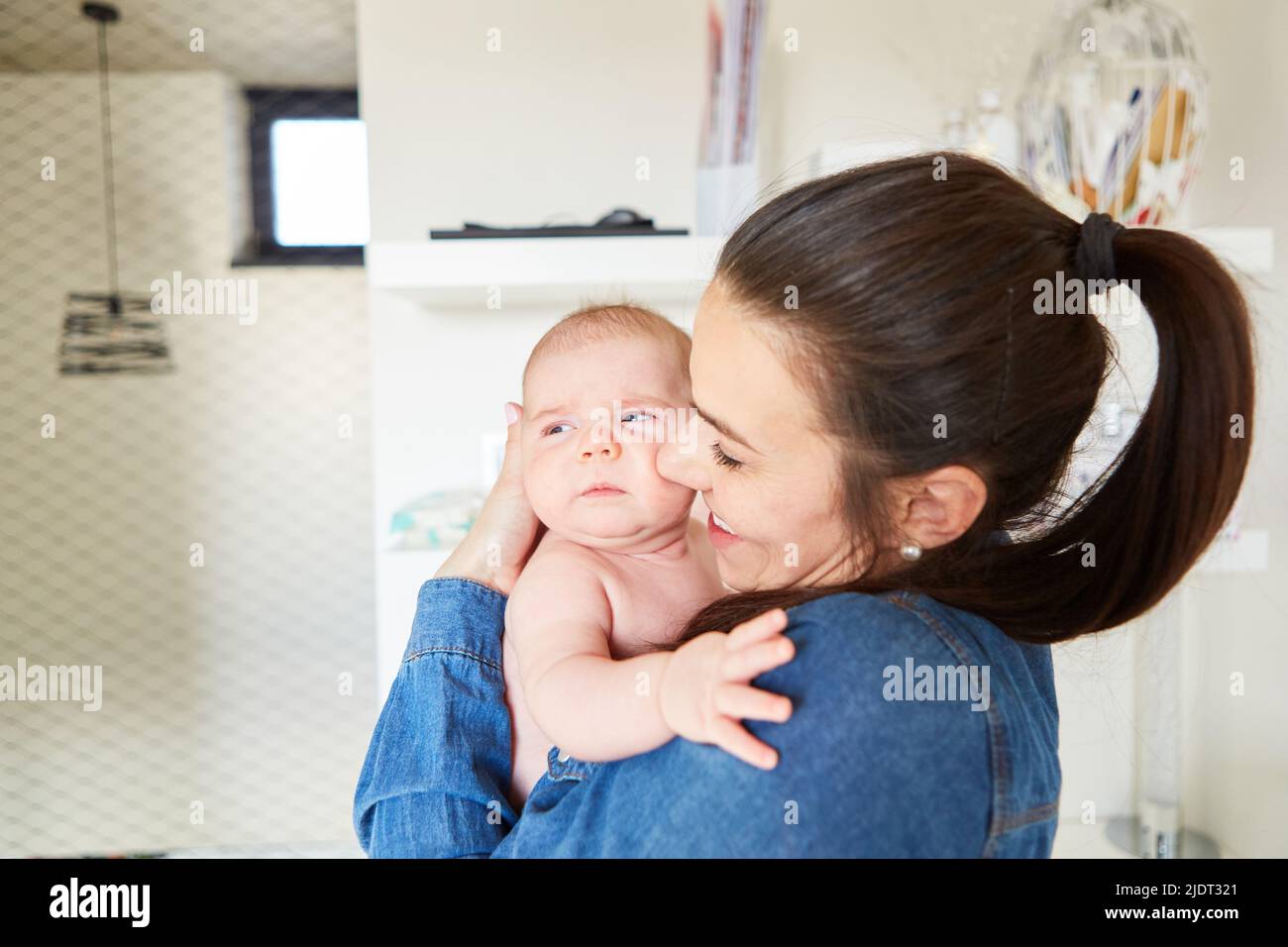 Happy mother lovingly holds her baby in her arms as a concept of motherly love Stock Photo