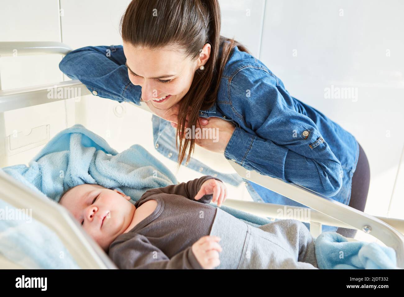 Happy single mother looking at her baby in bed as concept of motherly love Stock Photo