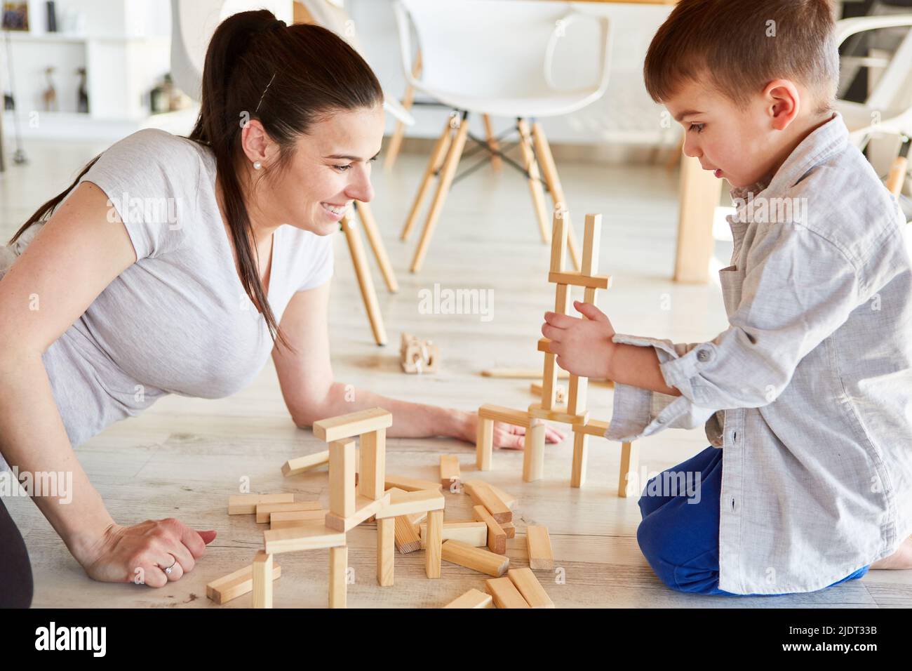 Mother and son play with wooden building blocks together on the living room floor Stock Photo