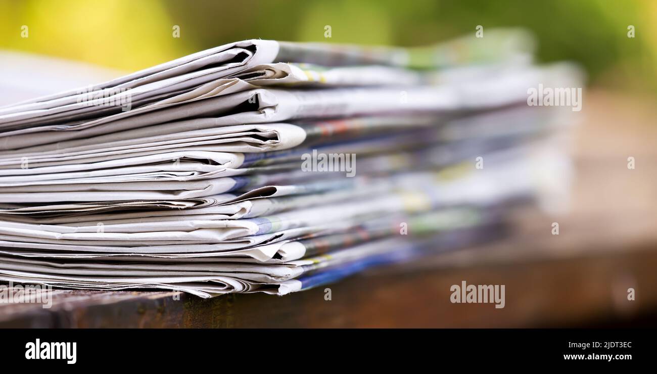 Newspaper stack on a wooden table, daily news banner Stock Photo