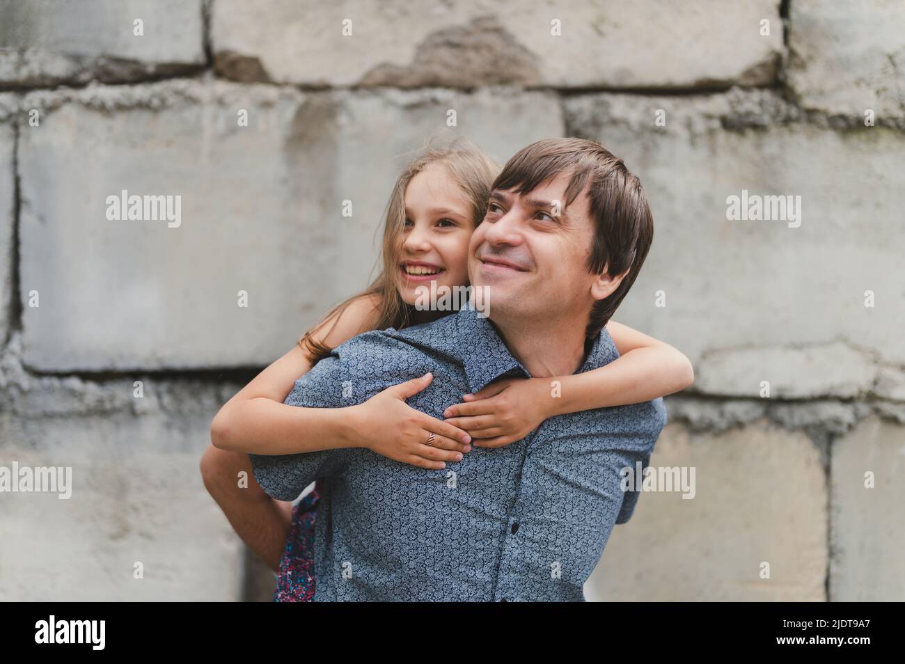 man dad having quality time with their kid daughter girl nine year old on his back. happy father playing with child. real life authentic day-to-day fa Stock Photo
