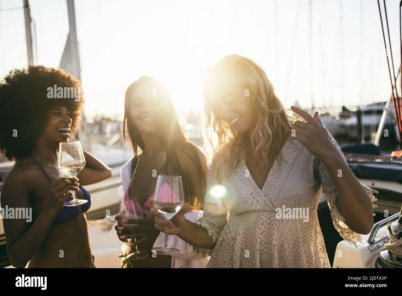 Young female friends having fun dancing together in sailing boat party - Focus on african girl hand Stock Photo