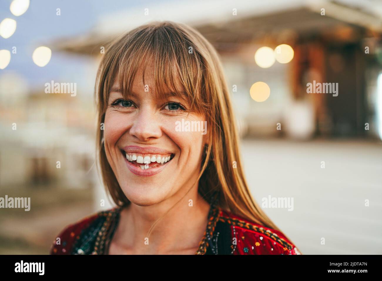 Young girl smiling on camera with beach bar on background - Focus on face Stock Photo