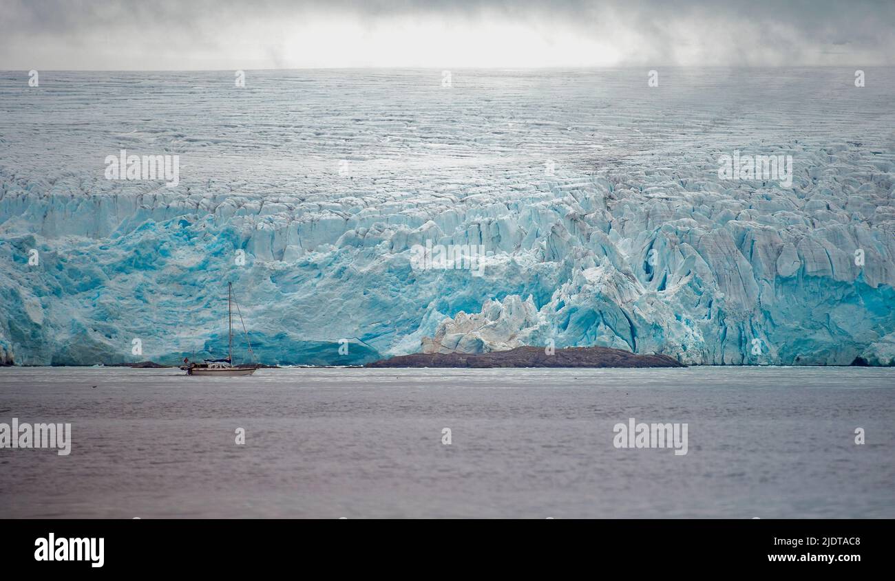 Sailboat in front of huge glacier at western coast of Spitsbergen, Svalbard in July 2012. Stock Photo