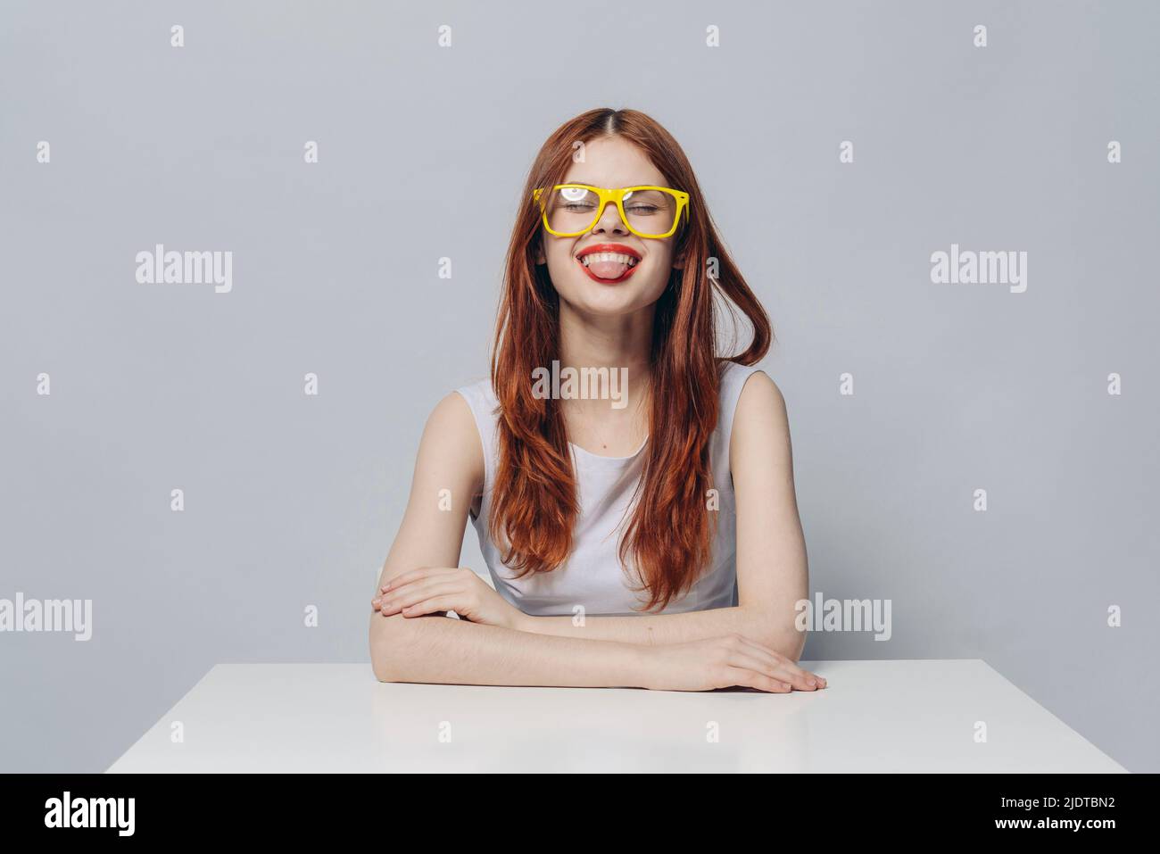 Caucasian woman sitting at table with tongue out Stock Photo