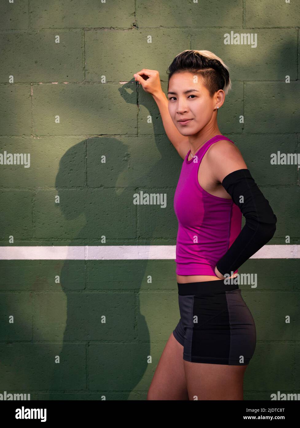 Portrait of athlete woman with amputated hand leaning against wall Stock Photo