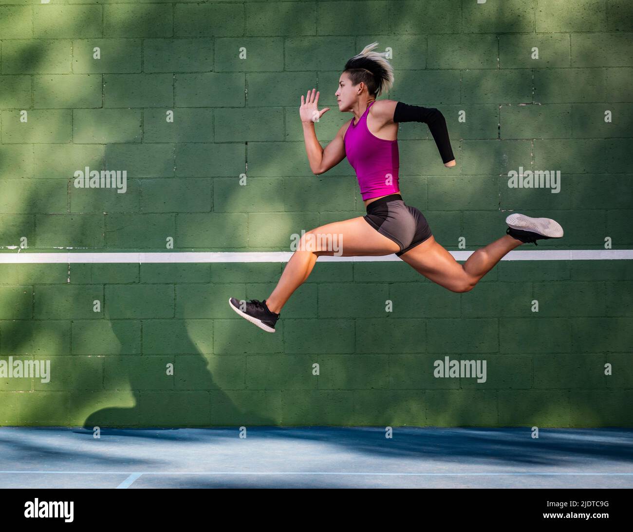 Athletic woman with prosthetic arm running against wall Stock Photo Alamy