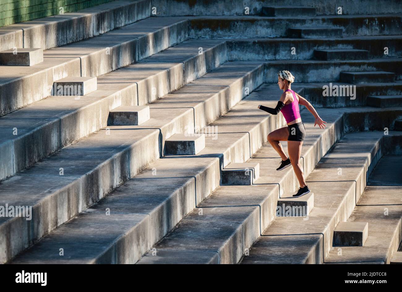 Athletic woman with amputated hand running up steps Stock Photo