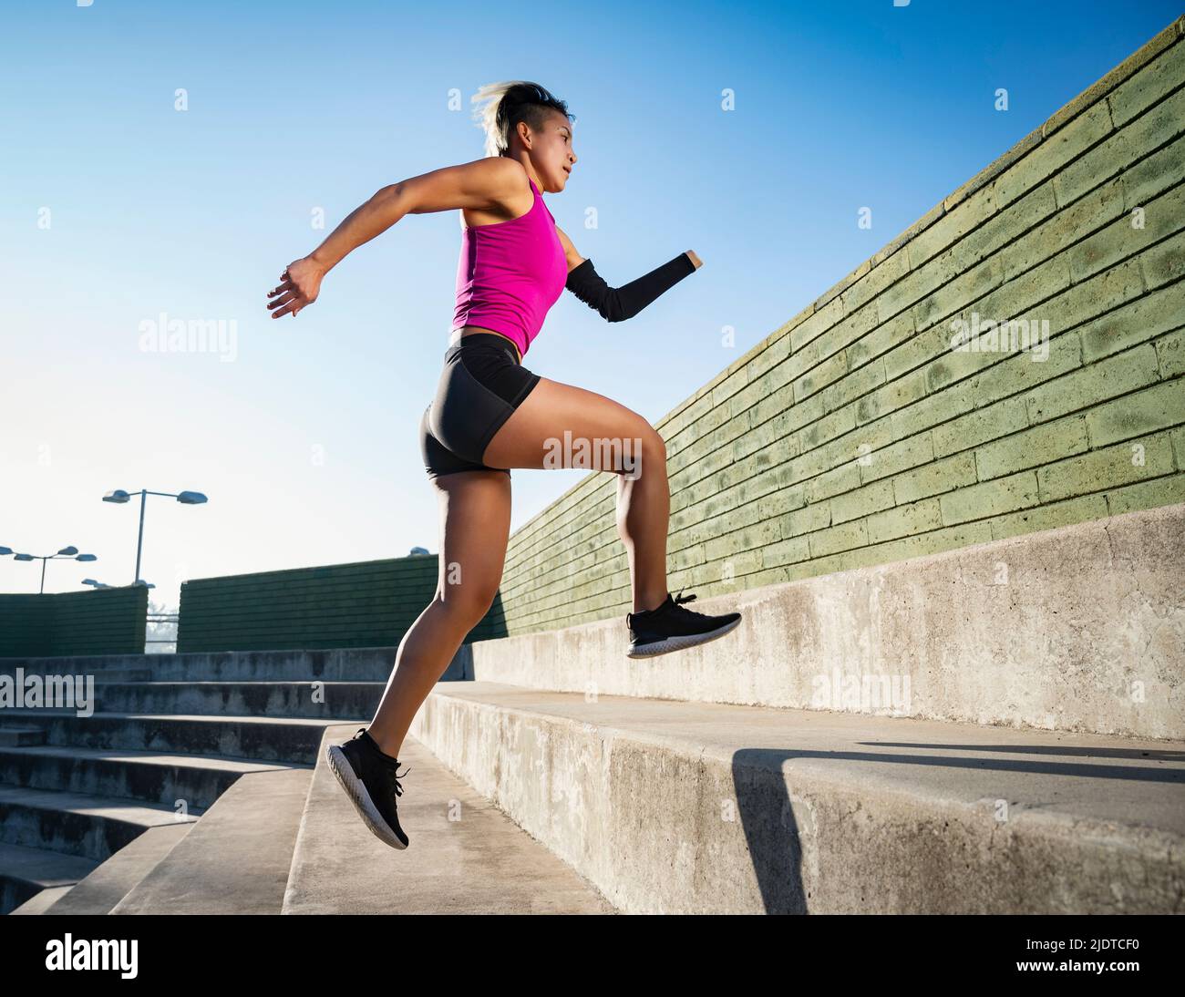 Athletic woman with amputated hand running up steps Stock Photo
