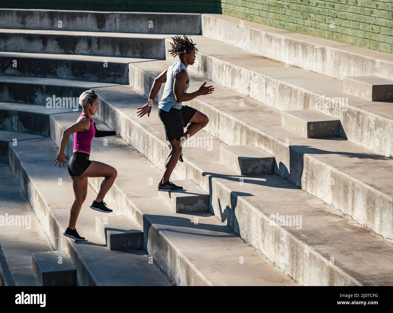 Athletic man and woman with amputated hand running up steps Stock Photo