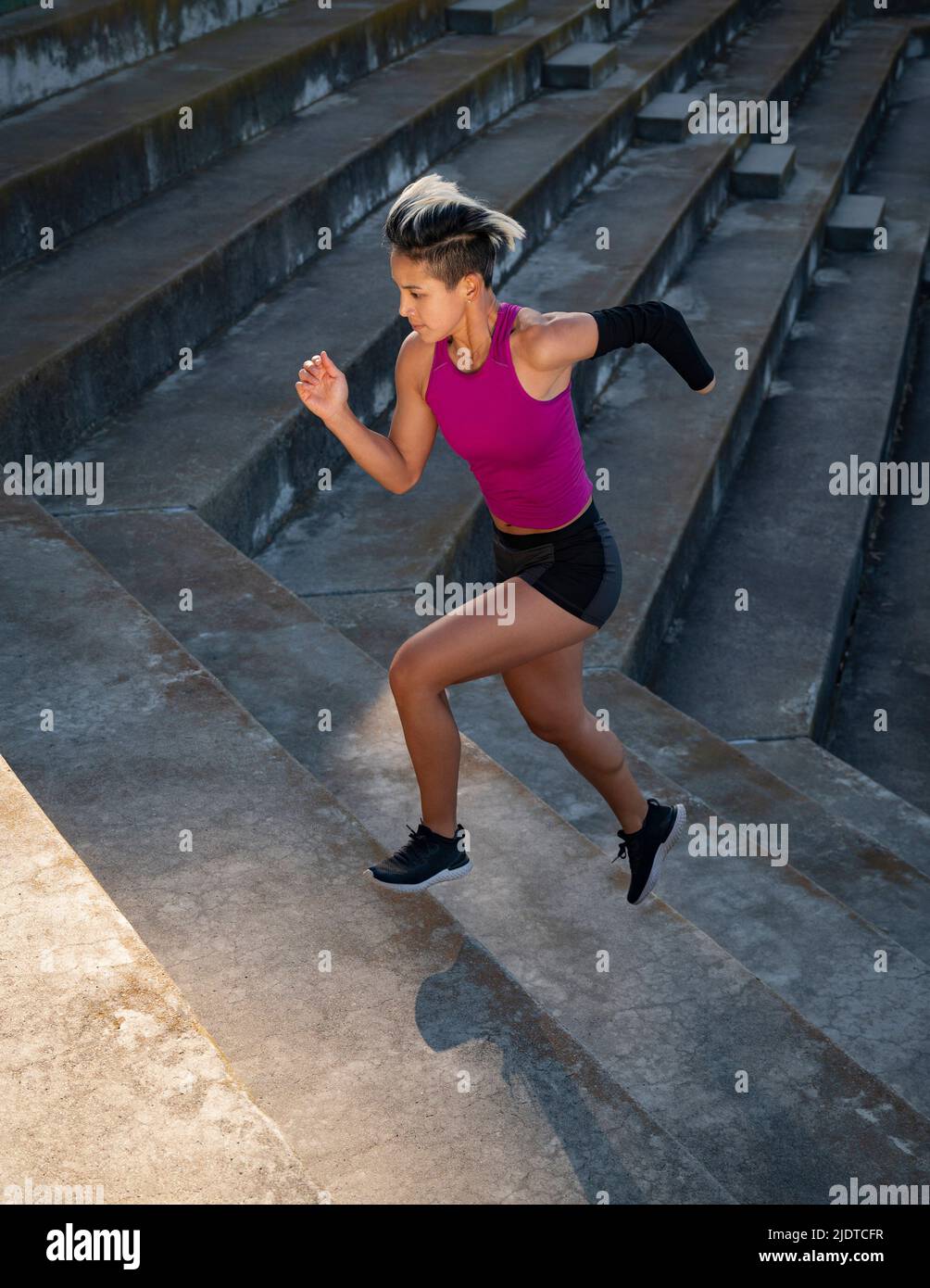 Athletic woman with amputated hand running up steps Stock Photo